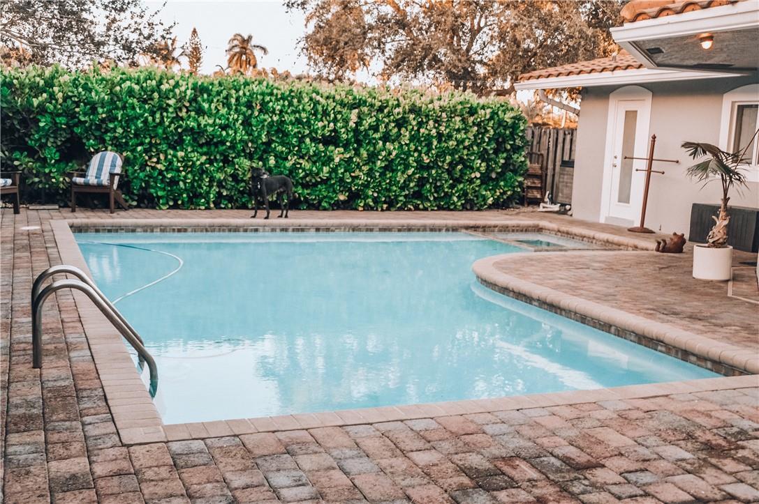 A backyard swimming pool with a paved deck, a hedge, and a house exterior — 5051 NE 24th Avenue, Lighthouse Point FL 33064, LIGHTHOUSE POINT, FL