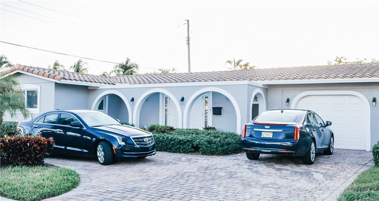 A single-story house with a tiled roof, arched entryway, and two parked cars in the driveway — 5051 NE 24th Avenue, Lighthouse Point FL 33064, LIGHTHOUSE POINT, FL