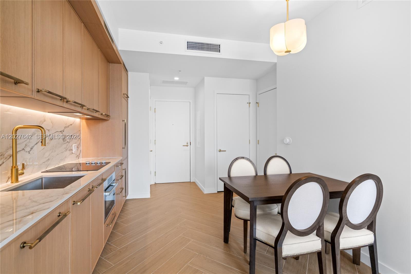 A kitchen with light wood cabinets, marble backsplash, and a small dining table — 2700 NW 2nd Ave # 717, Miami FL 33127, MIAMI, FL