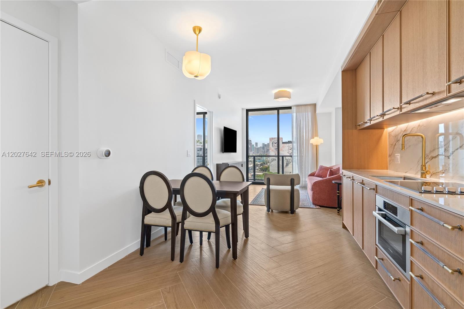 A modern open-concept apartment features a kitchen with wood cabinetry and a dining area — 2700 NW 2nd Ave # 717, Miami FL 33127, MIAMI, FL