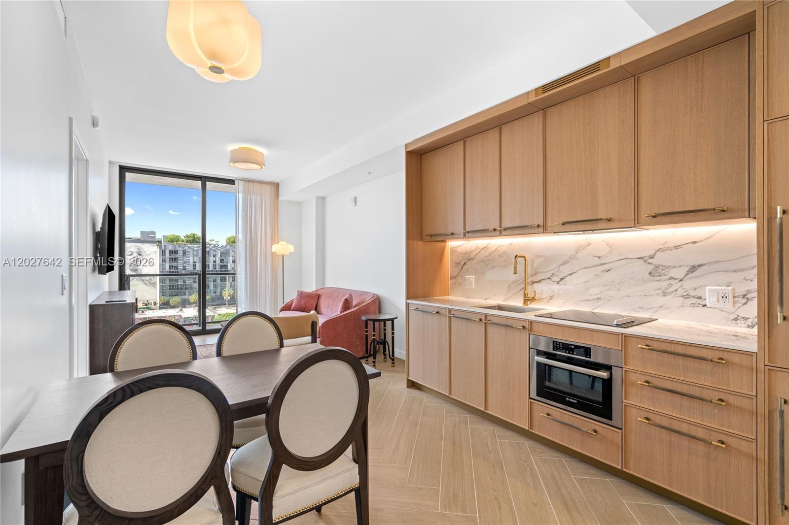 A modern kitchen with light wood cabinets and marble backsplash sits beside a dining area — 2700 NW 2nd Ave # 717, Miami FL 33127, MIAMI, FL