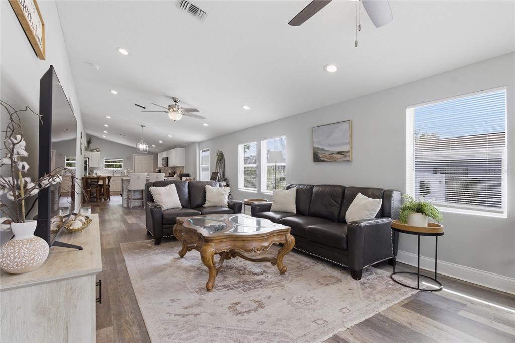 A living room features dark leather sofas, a wooden coffee table, and light wood flooring — 1613 E CHELSEA STREET, TAMPA, FL
