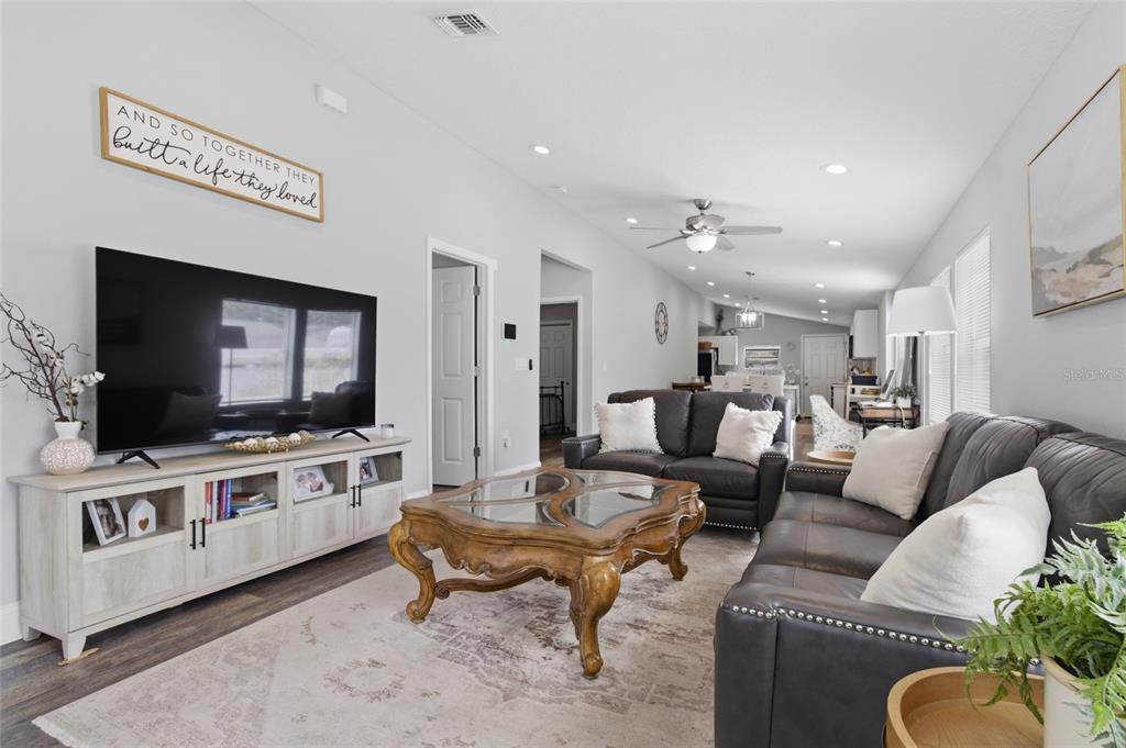 A living room features a large television, a wooden coffee table, and dark leather sofas — 1613 E CHELSEA STREET, TAMPA, FL