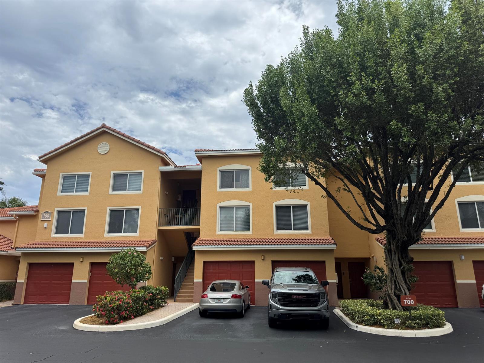 A three-story apartment building with yellow stucco walls, red tile roofs, and attached garages — 700 Scotia Drive # 103, Hypoluxo FL 33462, HYPOLUXO, FL