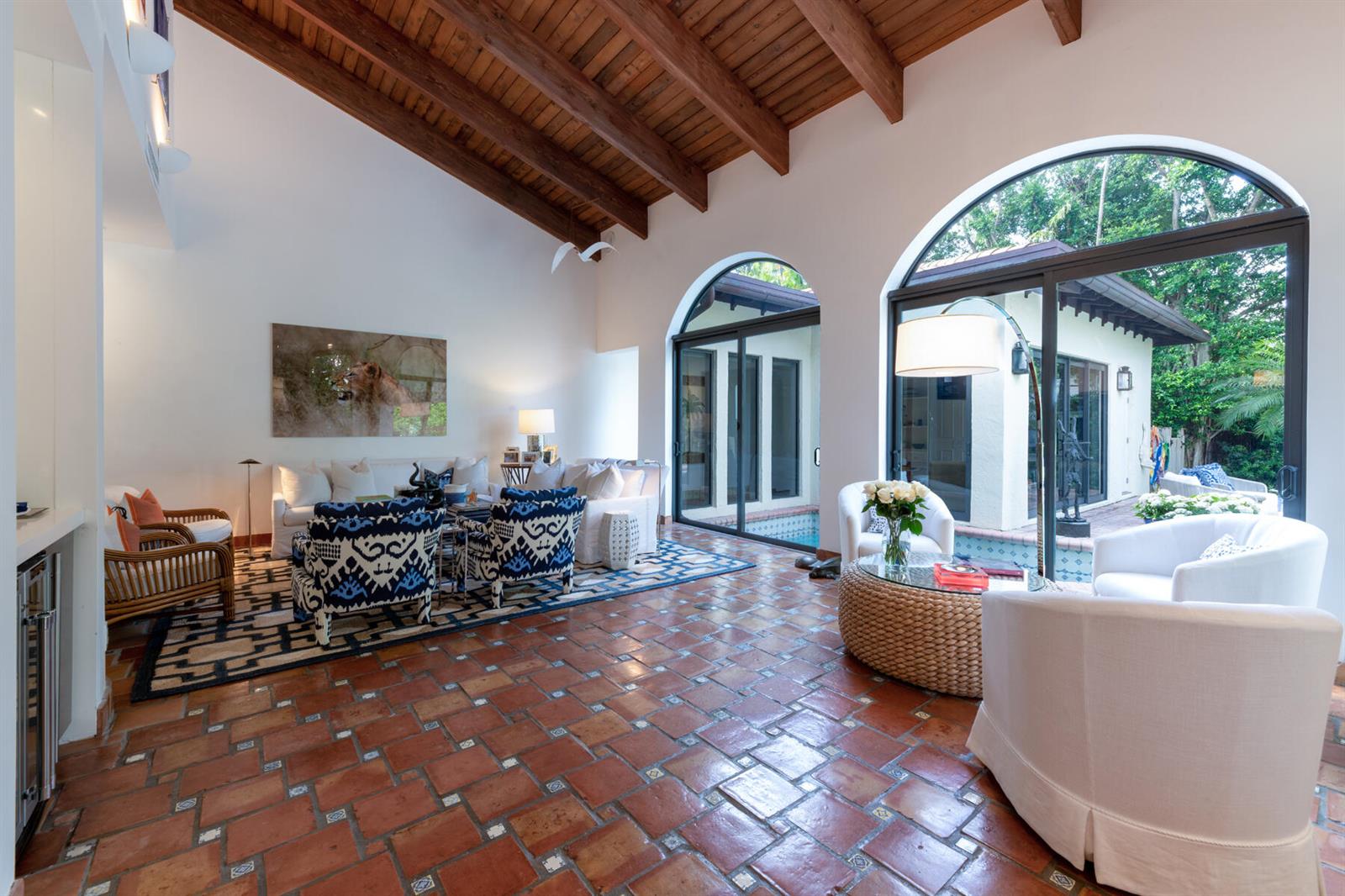 A living room with terracotta tile floors, vaulted wood-beamed ceilings, and arched glass doors — 264 Everglade Avenue, Palm Beach FL 33480, PALM BEACH, FL