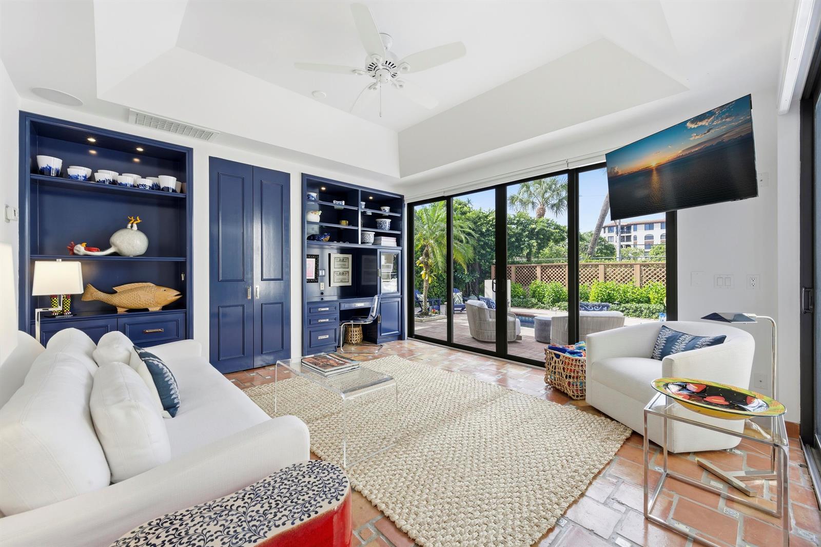 A living room features blue built-in shelving, a white sofa, and sliding doors to a patio — 264 Everglade Avenue, Palm Beach FL 33480, PALM BEACH, FL