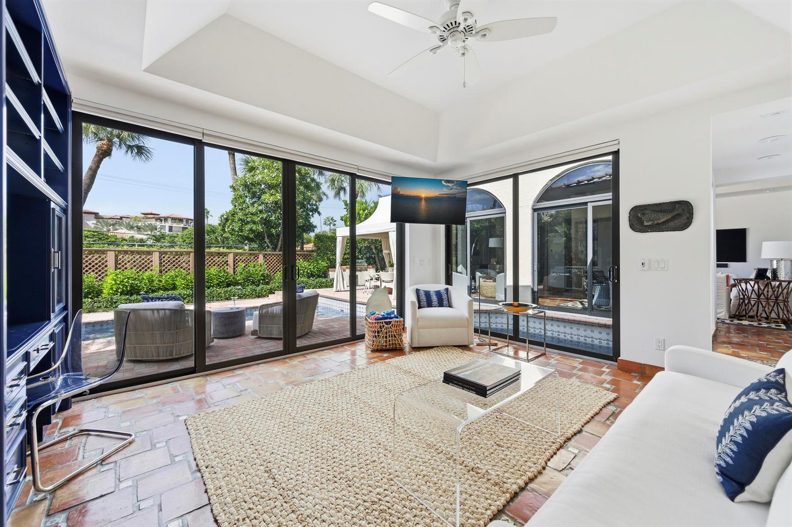 A sunlit living room features tile floors, a large area rug, and sliding glass doors — 264 Everglade Avenue, Palm Beach FL 33480, PALM BEACH, FL