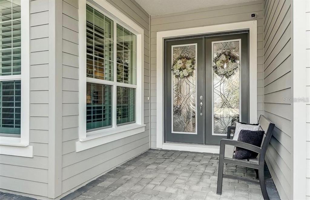 A gray front porch with a double glass door, a window, and a dark bench — 548 REGATTA WAY, BRADENTON, FL