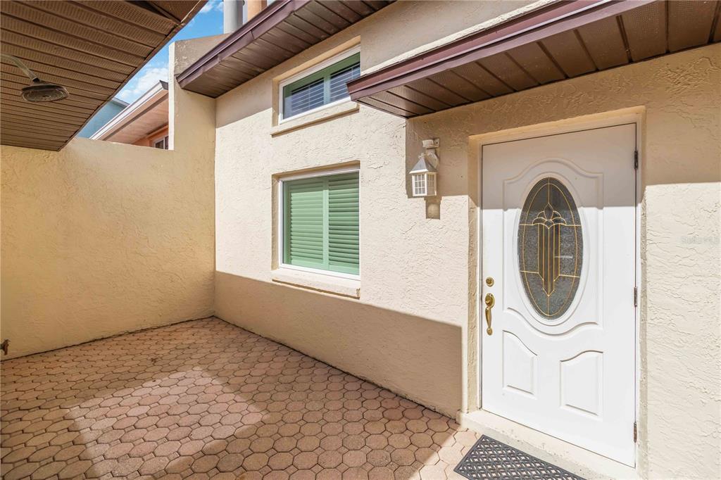 A paved entryway leads to a white front door with an oval glass insert — 292 CANAVERAL BEACH BOULEVARD, CAPE CANAVERAL, FL