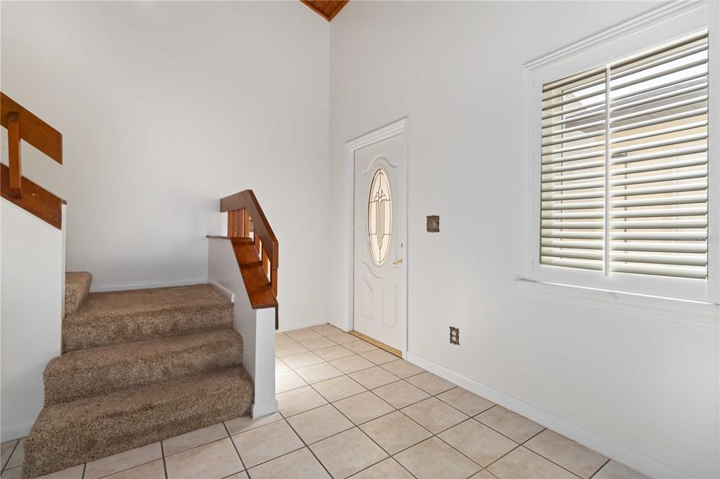An entryway features a carpeted staircase, a white front door, and tile flooring — 292 CANAVERAL BEACH BOULEVARD, CAPE CANAVERAL, FL