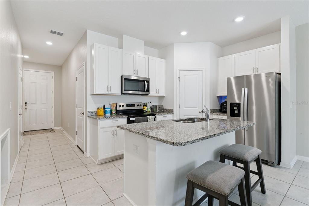 A kitchen with white cabinets, granite countertops, stainless steel appliances, and a central island — 1106 ARBOUR VERDE COURT, TAMPA, FL