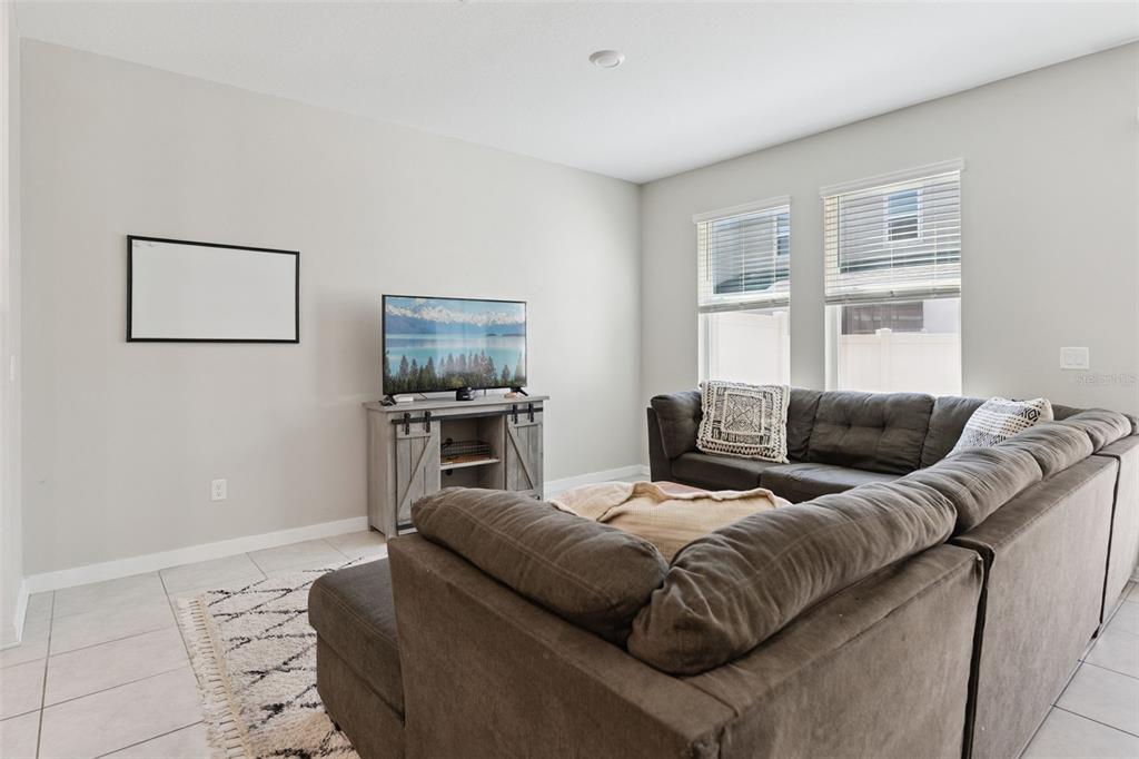 A living room features a gray sectional sofa, a television on a media console, and windows — 1106 ARBOUR VERDE COURT, TAMPA, FL