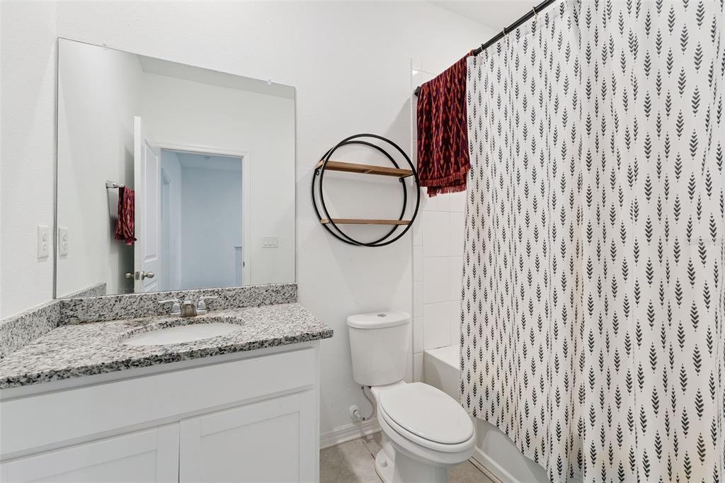 A bathroom features a granite vanity, white cabinets, a round wall shelf, and a patterned curtain — 1106 ARBOUR VERDE COURT, TAMPA, FL