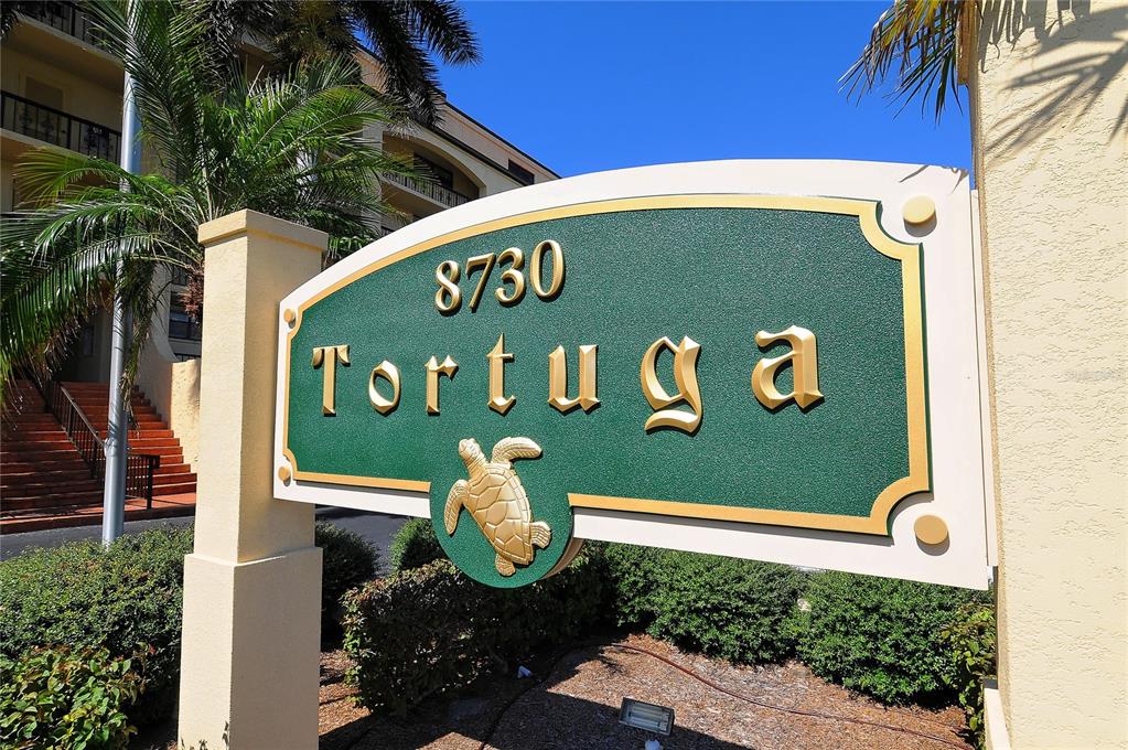 A green sign with the word Tortuga and a turtle icon stands outside a building — 8710 MIDNIGHT PASS ROAD UNIT 405, SARASOTA, FL