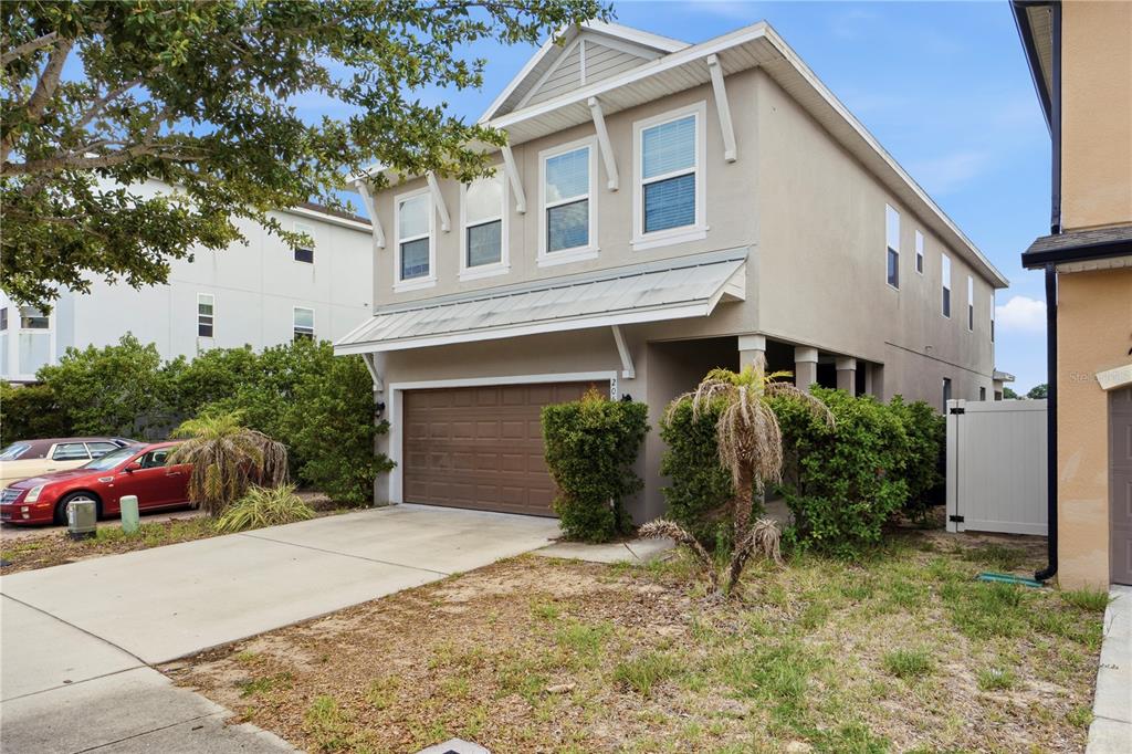 A two-story house with a beige exterior, a brown garage door, and a concrete driveway — 205 ABERDEEN STREET, DAVENPORT, FL