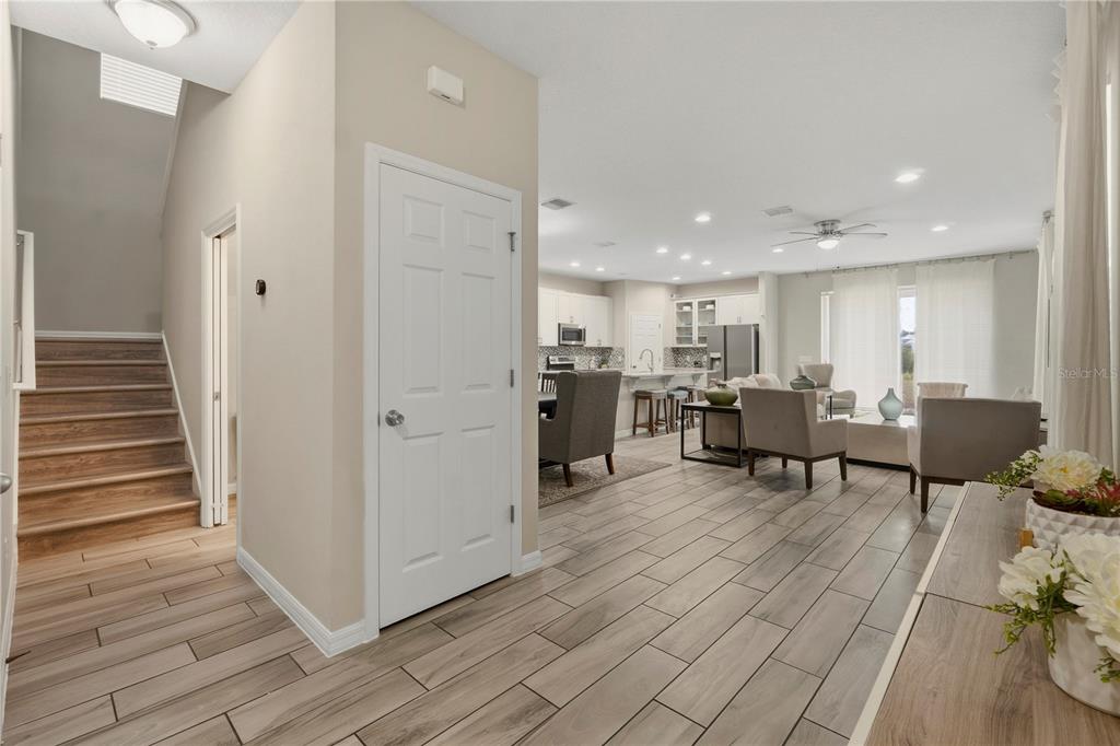 An open-concept living room and kitchen feature light wood-look tile flooring and neutral furniture — 205 ABERDEEN STREET, DAVENPORT, FL