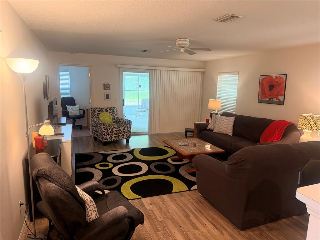 A living room features wood-look flooring, a patterned area rug, and a sliding glass door — 6157 W CANNONDALE DRIVE, CRYSTAL RIVER, FL