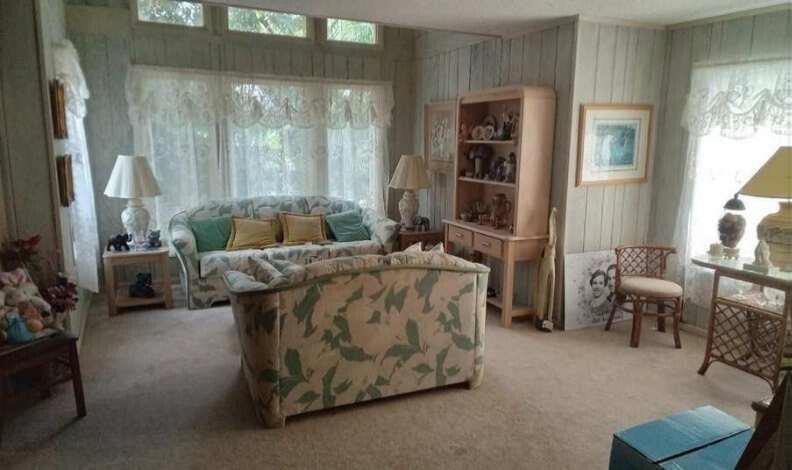 A living room features floral sofas, wood-paneled walls, a hutch, and large windows with curtains — 596 Greenwood Drive, Jupiter FL 33458, JUPITER, FL