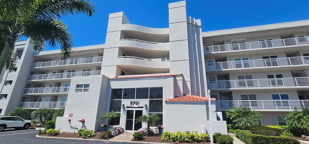 A multi-story apartment building with white balconies and a central glass-enclosed entrance — 5701 BAHIA DEL MAR CIRCLE UNIT 408, ST PETERSBURG, FL