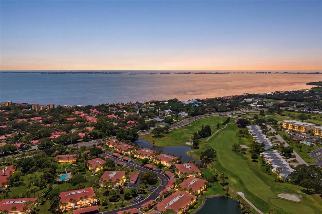 An aerial view shows a residential complex with red-roofed buildings situated near a golf course — 3500 EL CONQUISTADOR PARKWAY UNIT 332, BRADENTON, FL