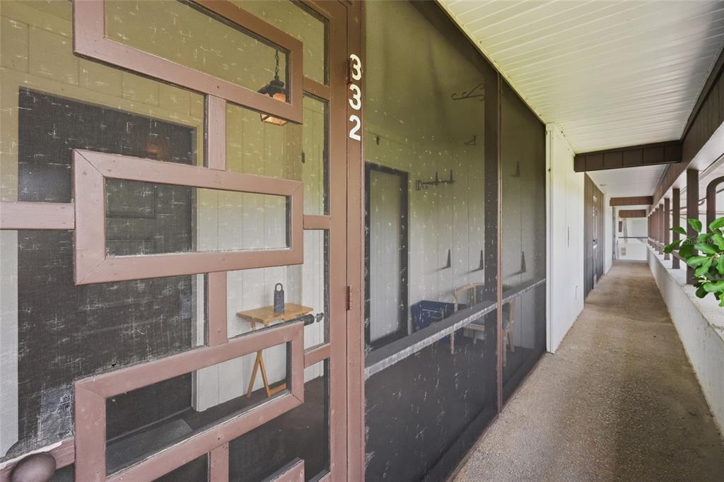 A screened-in entryway with a geometric patterned door leads to a long outdoor walkway — 3500 EL CONQUISTADOR PARKWAY UNIT 332, BRADENTON, FL