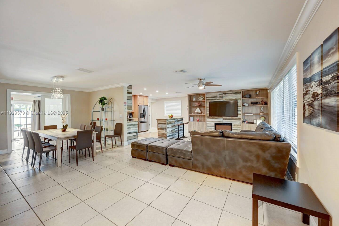 An open-concept living and dining area features tile flooring, a large sectional, and kitchen island — 1228 Johnson St, Hollywood FL 33019, HOLLYWOOD, FL