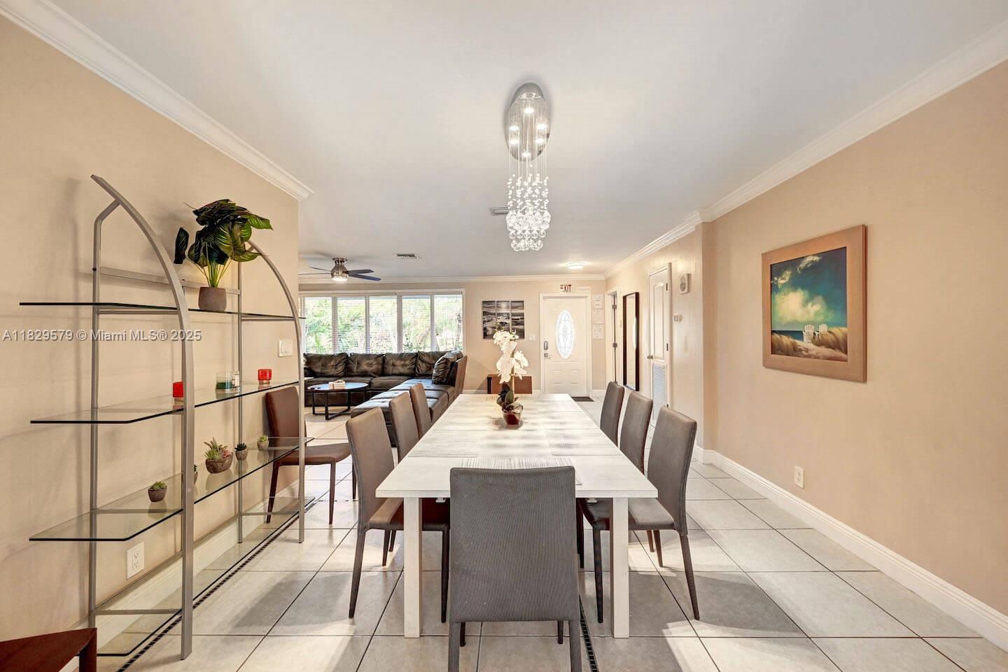 A dining room features a long white table, gray chairs, and a crystal chandelier — 1228 Johnson St, Hollywood FL 33019, HOLLYWOOD, FL
