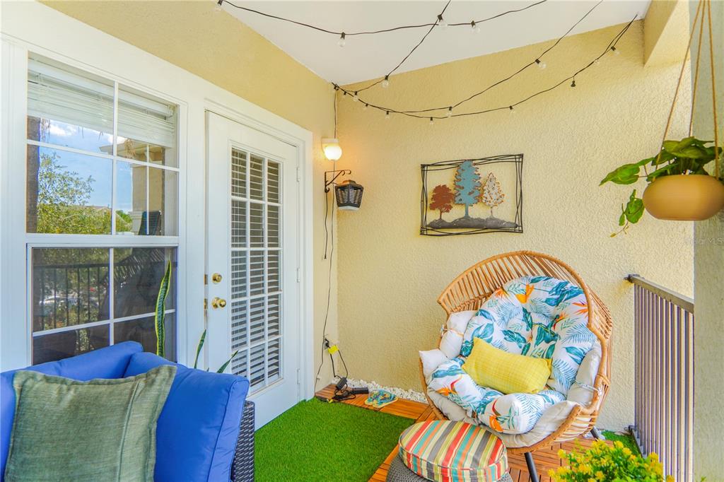 A balcony with artificial turf, a wicker egg chair, and string lights — 3605 CONROY ROAD UNIT 535, ORLANDO, FL