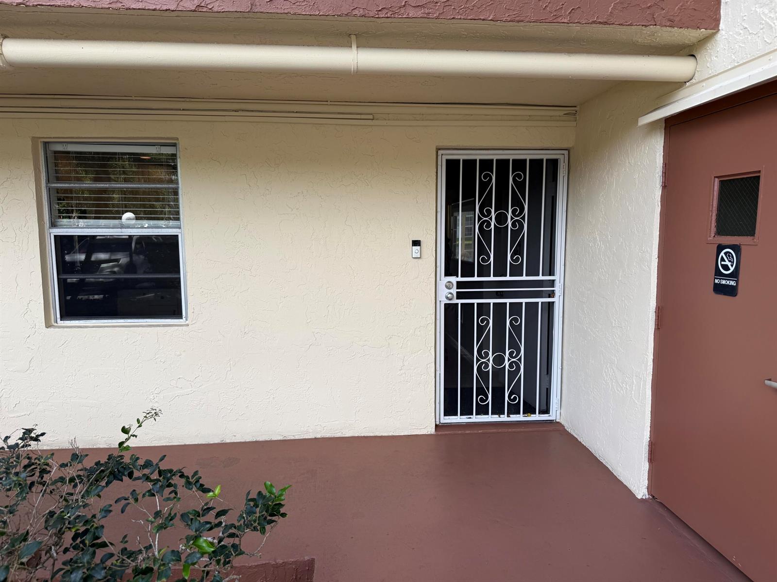 An exterior view of a building entrance with a window, a security door, and a sign — 111 SE 3rd Avenue # 108, Dania Beach FL 33004, DANIA BEACH, FL