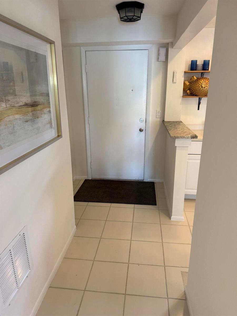 A tiled entryway features a white front door, a wall-mounted picture, and a small shelf — 111 SE 3rd Avenue # 108, Dania Beach FL 33004, DANIA BEACH, FL