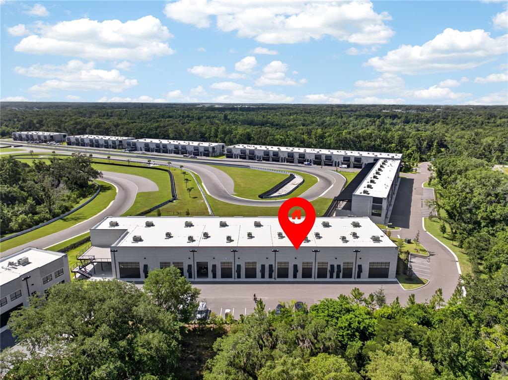 An aerial view shows a commercial building complex situated next to a paved racetrack — 6500 MOTOR ENCLAVE WAY UNIT 1514, TAMPA, FL