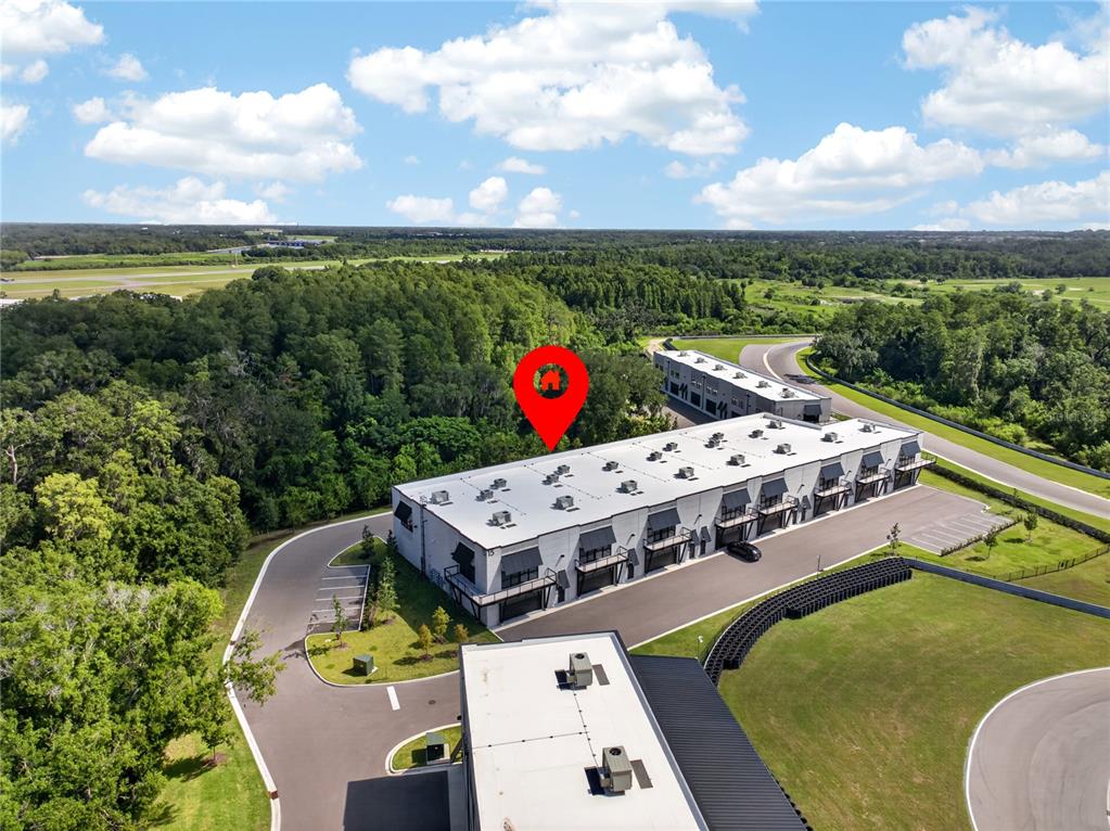 An aerial view shows a modern commercial building complex situated next to a racetrack — 6500 MOTOR ENCLAVE WAY UNIT 1514, TAMPA, FL