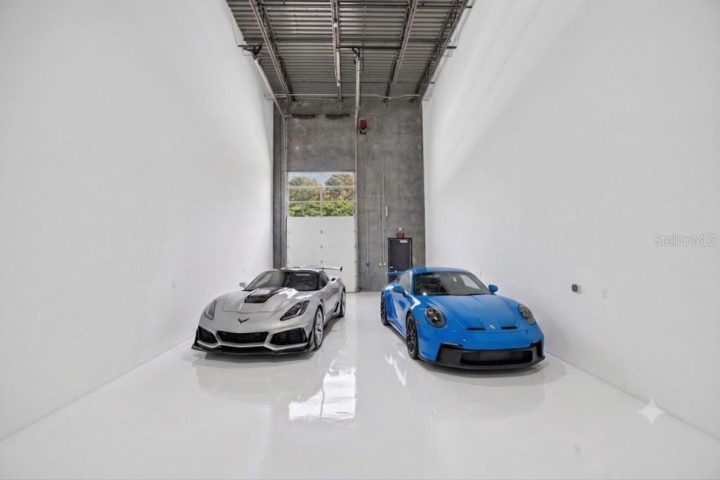 A high-ceilinged white garage with a concrete wall and two sports cars parked inside — 6500 MOTOR ENCLAVE WAY UNIT 1514, TAMPA, FL