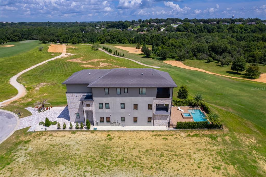 An aerial view shows a multi-story house with a pool overlooking a golf course — 16338 RAVENNA COURT, BELLA COLLINA, FL