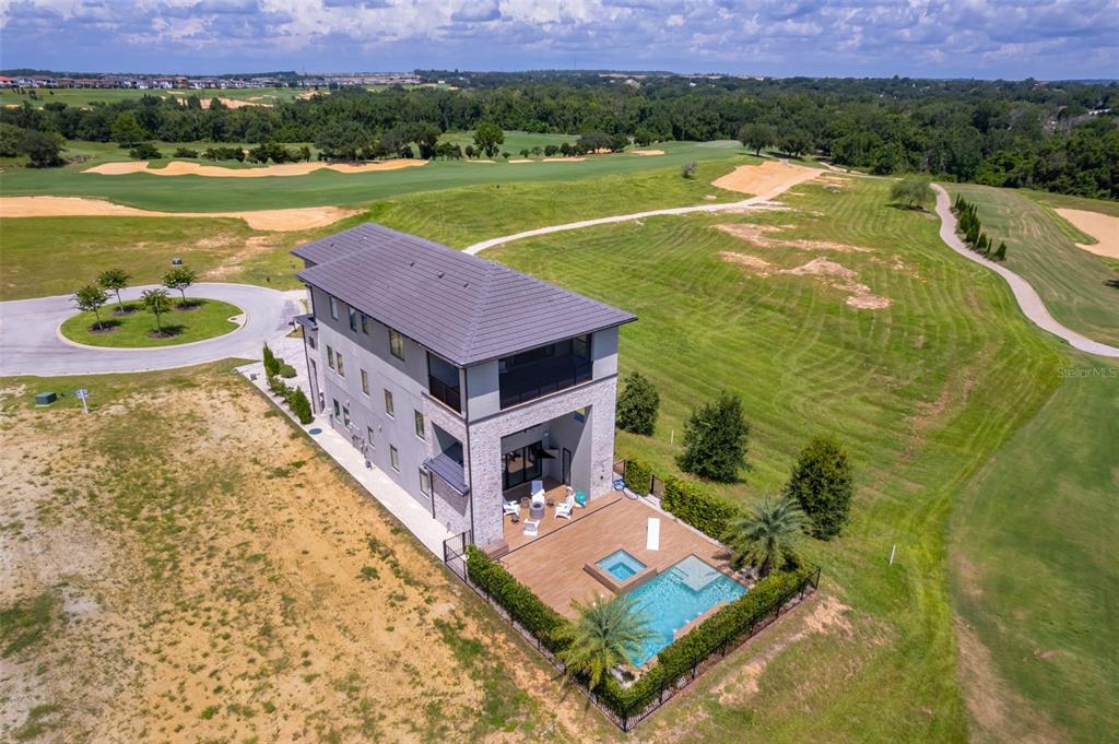 An aerial view shows a three-story house with a pool and deck overlooking a golf course — 16338 RAVENNA COURT, BELLA COLLINA, FL