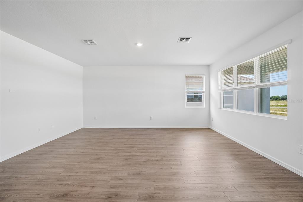 An empty room with white walls, light wood-look flooring, and several windows — 1749 S HUMMINGBIRD ROAD, WINTER HAVEN, FL