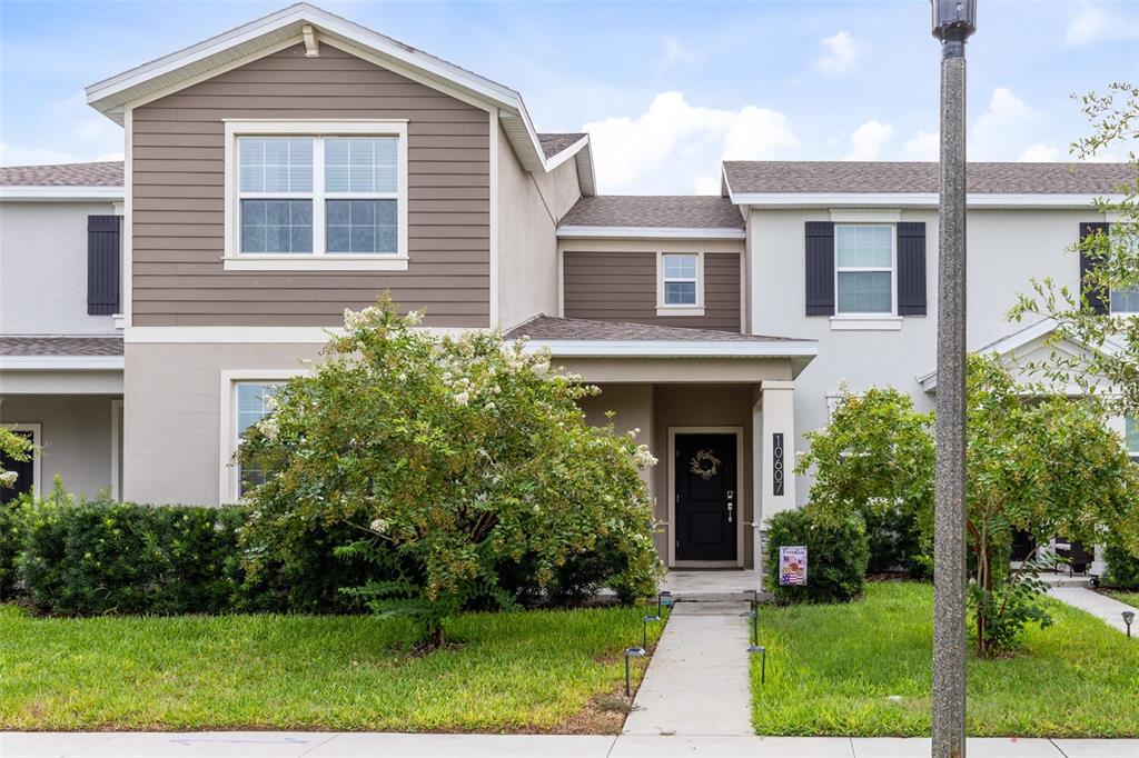 A two-story townhouse exterior features brown siding, a covered entryway, and a front walkway — 10607 WORDS DRIVE, WINTER GARDEN, FL