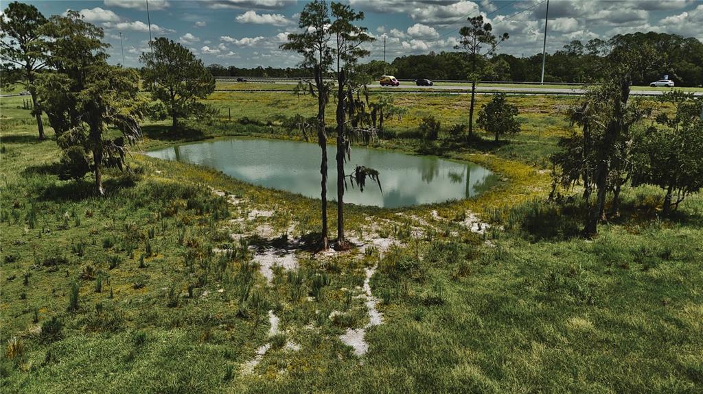 An aerial view shows a small pond surrounded by grassy fields and trees near a highway — 4802 NW 50TH ROAD, STARKE, FL