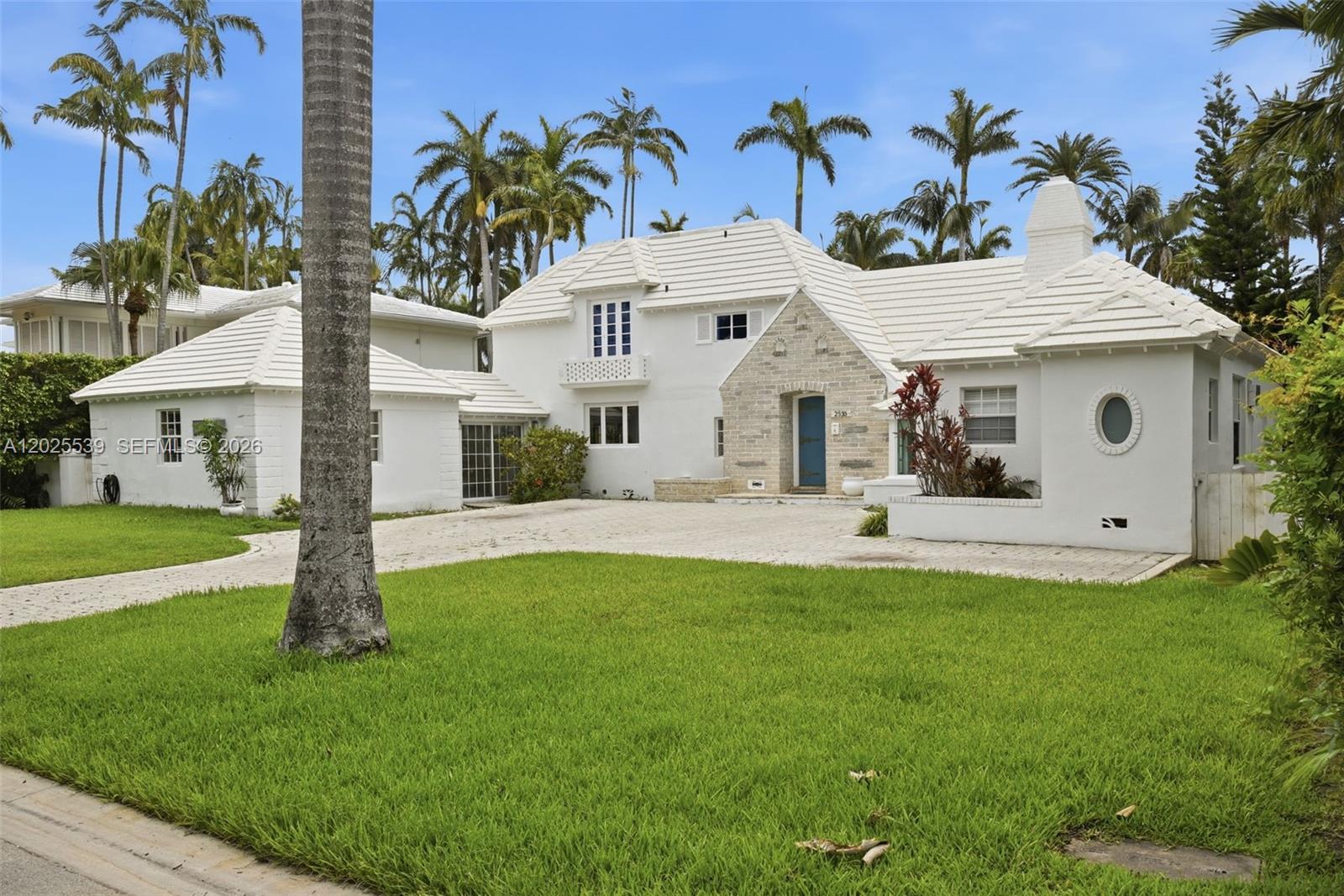 A white two-story house with a stone entryway and a paved driveway sits on grass — 2535 Sunset Dr, Miami Beach FL 33140, MIAMI BEACH, FL