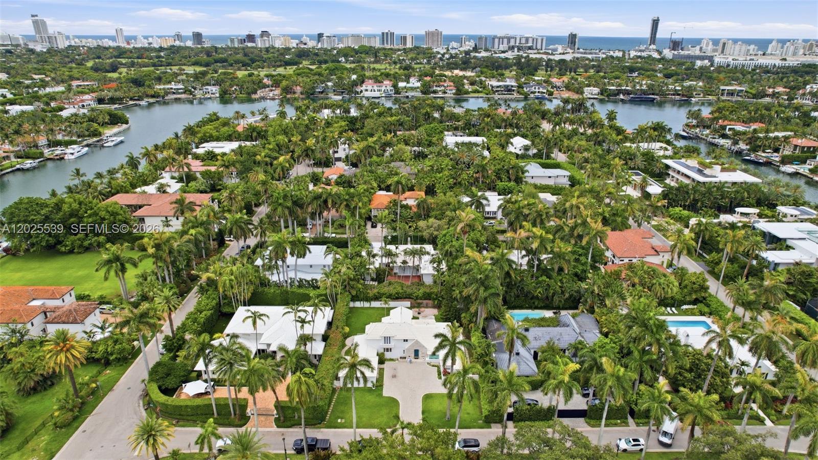 An aerial view shows a residential neighborhood with lush trees, swimming pools, and waterfront access — 2535 Sunset Dr, Miami Beach FL 33140, MIAMI BEACH, FL