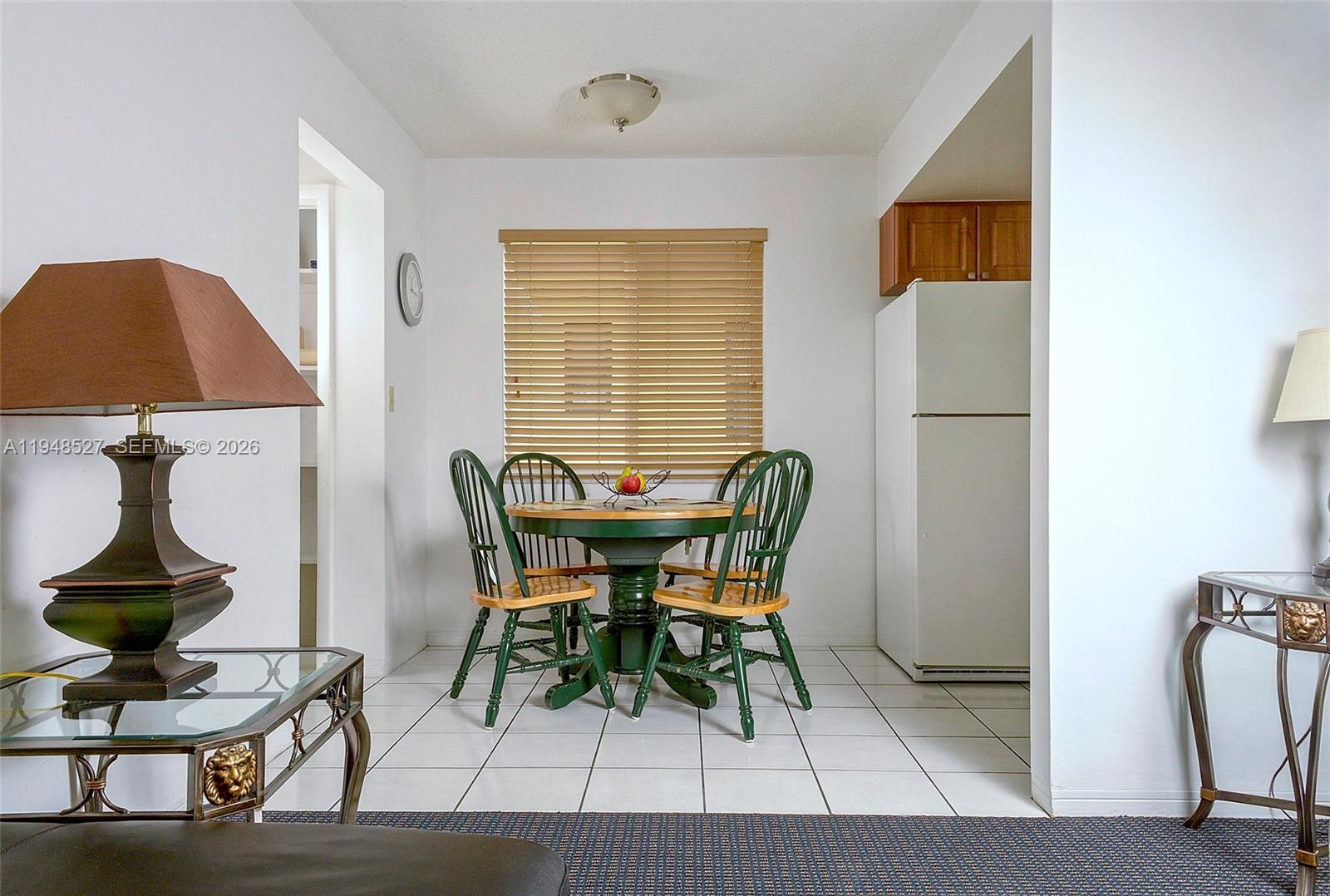 A dining area features a round green table, matching chairs, and white tile flooring — 1748 Rodman St # 117, Hollywood FL 33020, HOLLYWOOD, FL