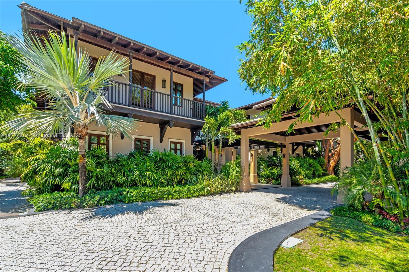 A two-story house with a balcony and a covered driveway entrance surrounded by lush landscaping — 9 Harbor Pt, Key Biscayne FL 33149, KEY BISCAYNE, FL