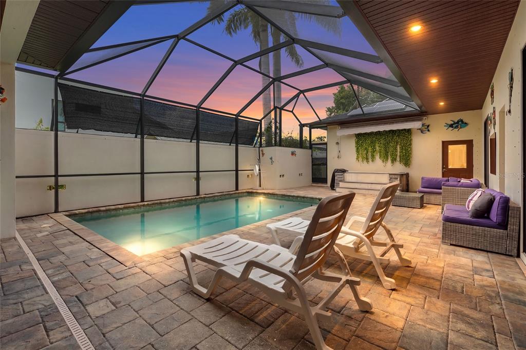 A screened-in patio features a swimming pool, lounge chairs, and outdoor seating on pavers — 1775 7TH STREET, SARASOTA, FL