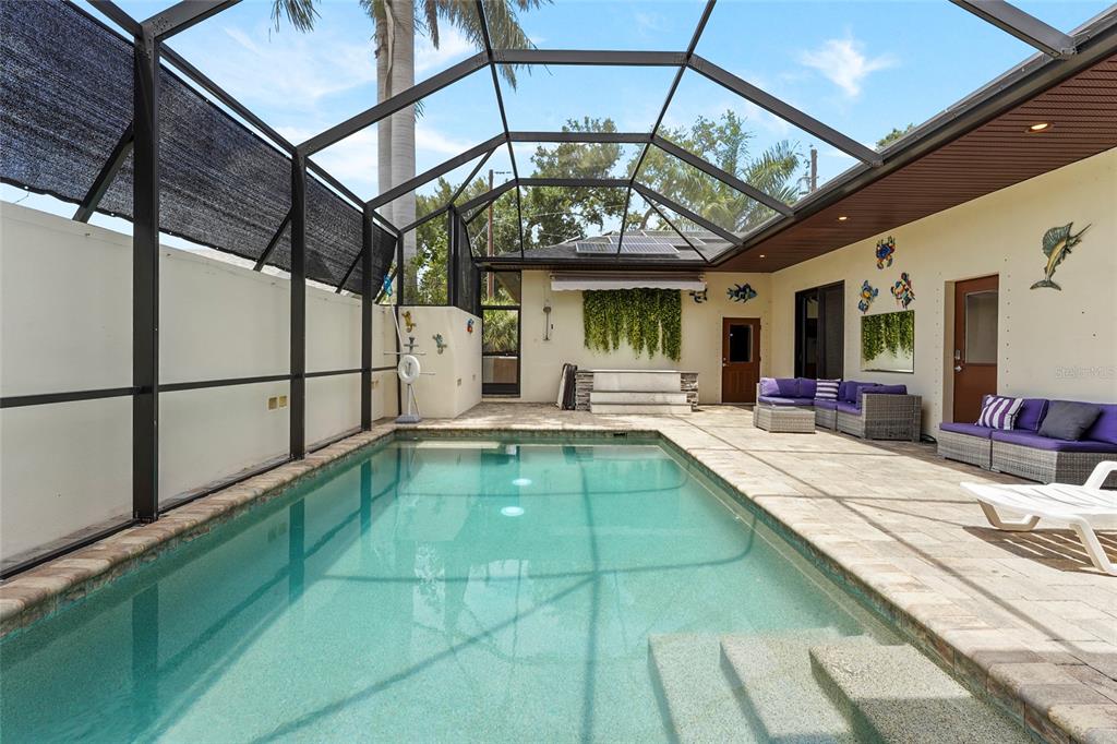 A screened-in swimming pool area with stone decking, outdoor furniture, and a covered patio — 1775 7TH STREET, SARASOTA, FL