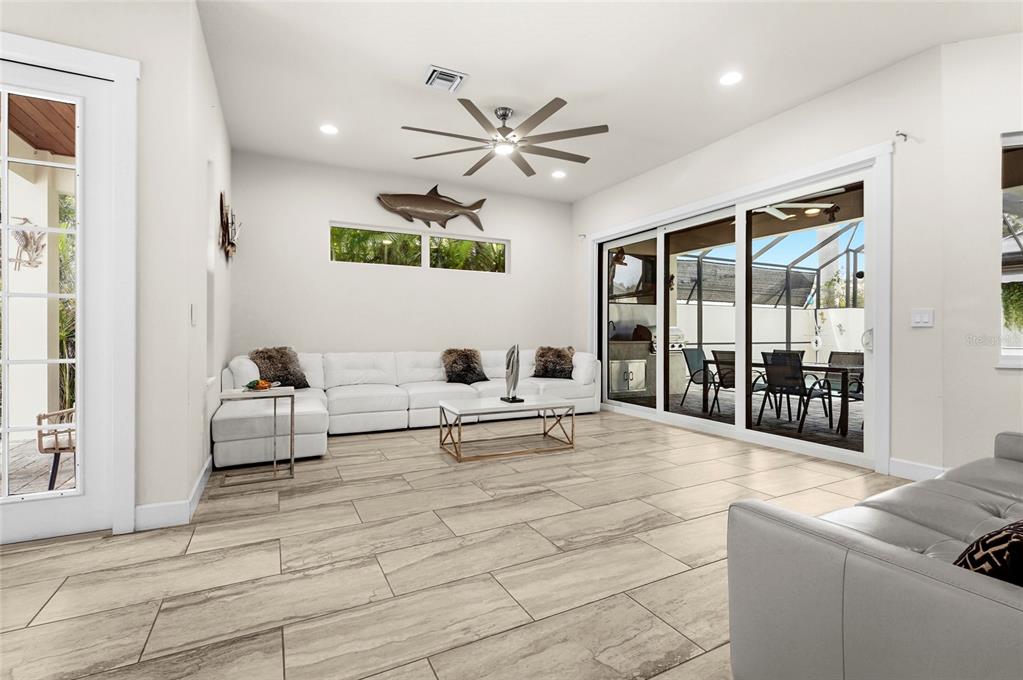 A living room with light tile floors, a white sectional sofa, and sliding glass doors — 1775 7TH STREET, SARASOTA, FL