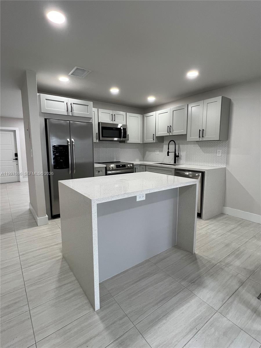 A modern kitchen features light gray cabinets, stainless steel appliances, and a central quartz island — 3826 SW 107th Ave # 2, Miami FL 33165, MIAMI, FL