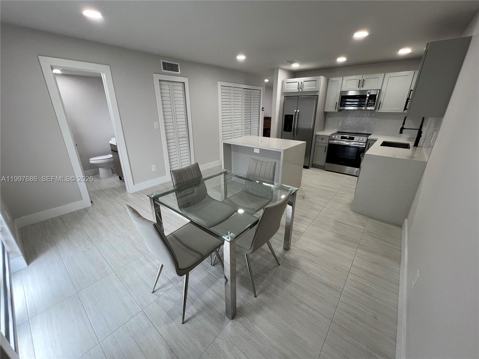 A modern kitchen features white cabinetry, stainless steel appliances, a glass dining table, and tile flooring — 3826 SW 107th Ave # 2, Miami FL 33165, MIAMI, FL