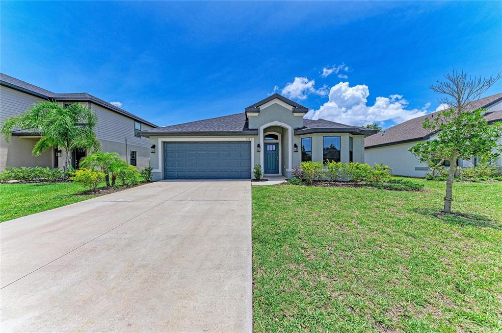 A single-story house with a gray garage, teal front door, and a concrete driveway — 9421 43RD COURT E, PARRISH, FL