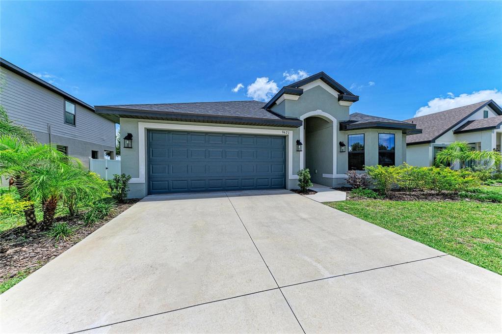 A single-story house with a two-car garage, light green stucco exterior, and a concrete driveway — 9421 43RD COURT E, PARRISH, FL