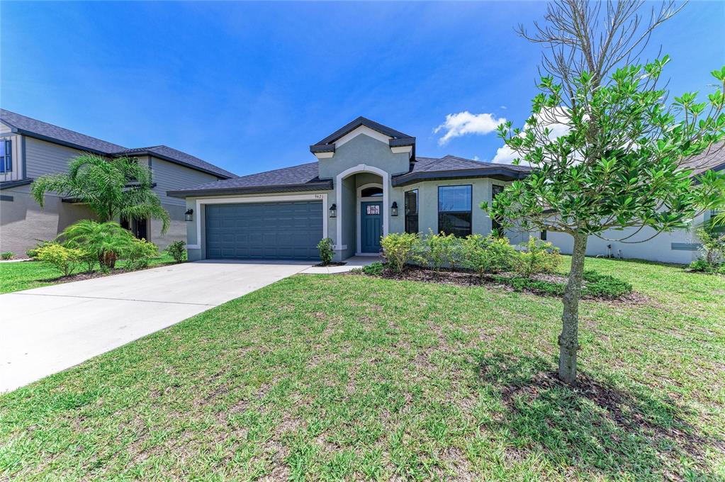 A single-story house with a blue garage door, a covered entryway, and a grassy front yard — 9421 43RD COURT E, PARRISH, FL